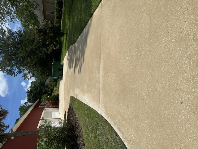 Long side driveway with freshly cleaned concrete beside a red brick home