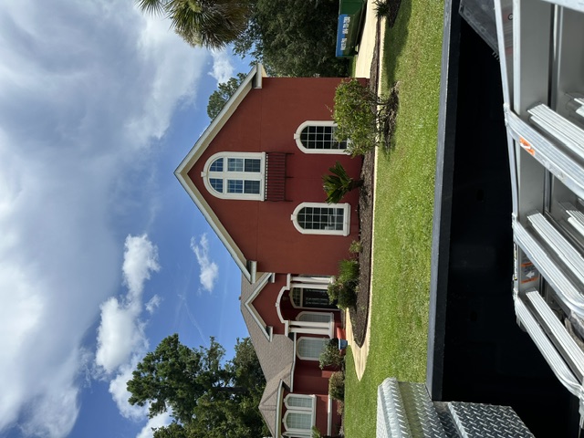 Two-story red stucco home with clean exterior walls after house washing