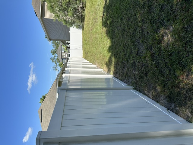 The same backyard fence bright white and clean after soft washing